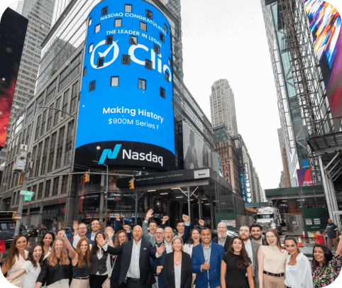The Clio team celebrating in front of a Nasdaq billboard in Times Square that displays the Clio logo.