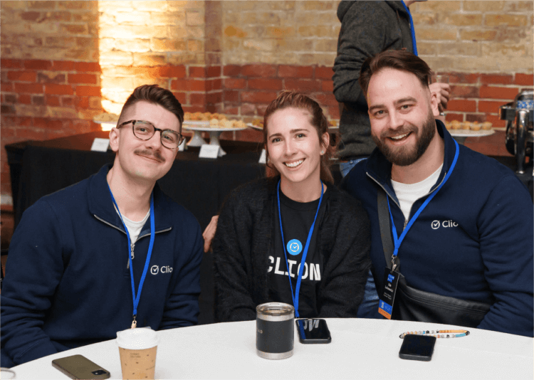 Three smiling Clio employees at a company event in the Toronto office.