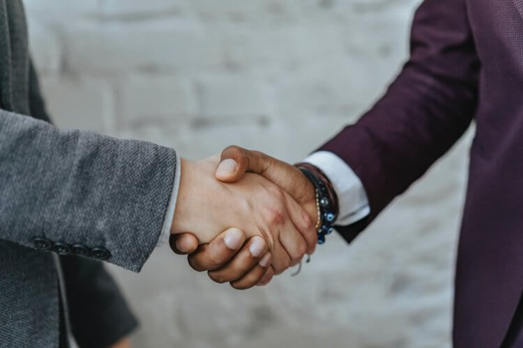 Two people shaking hands in front of a wall