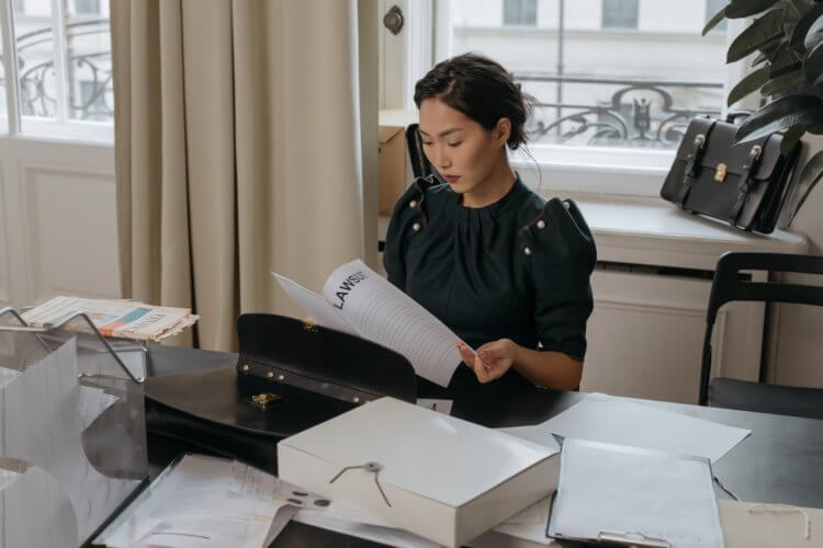 A female-presenting lawyer reviewing legal malpractice claim documents at a desk in an office