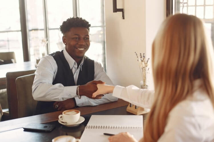 two people shaking hands while sitting down and having an interview