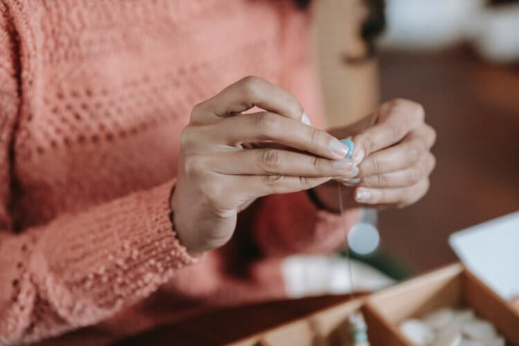 closeup of a person making jewelry with beads