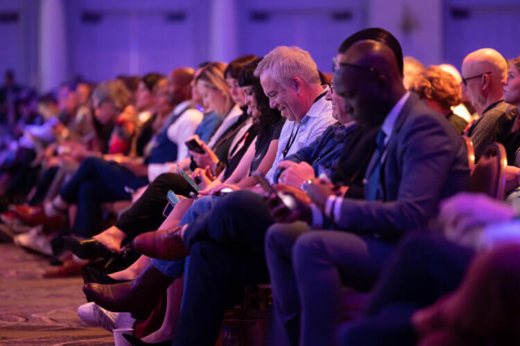 Attendees sitting at the 2022 Clio Cloud Conference and taking notes on their phones