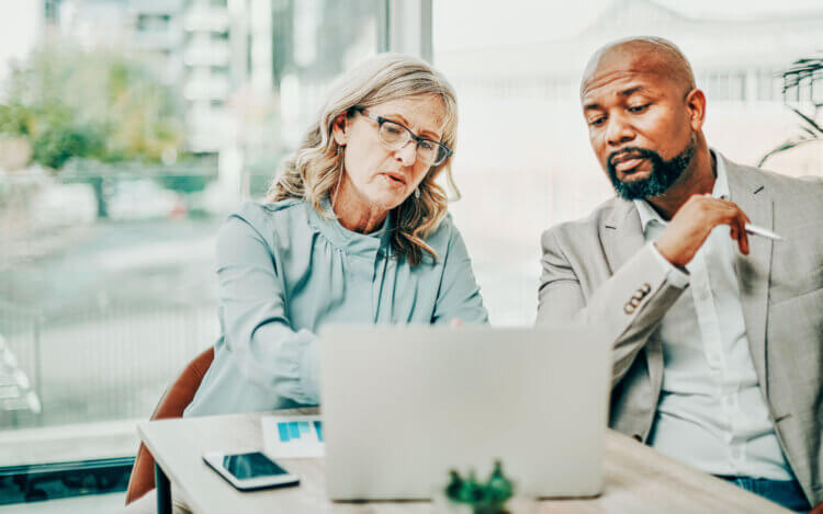 Photo of two legal professionals sitting in front of a laptop looking at document management software