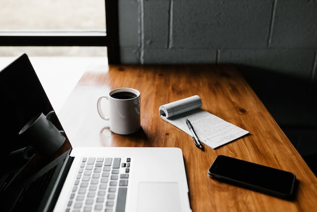 computer, coffee, notes on a desk.